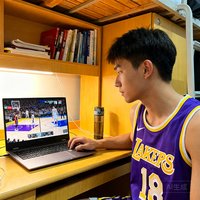 一位20岁出头的大学男生，穿着NBA湖人队紫金球衣，坐在宿舍书桌前用笔记本电脑观看178直播，屏幕上同时显示NBA和CBA两场比赛